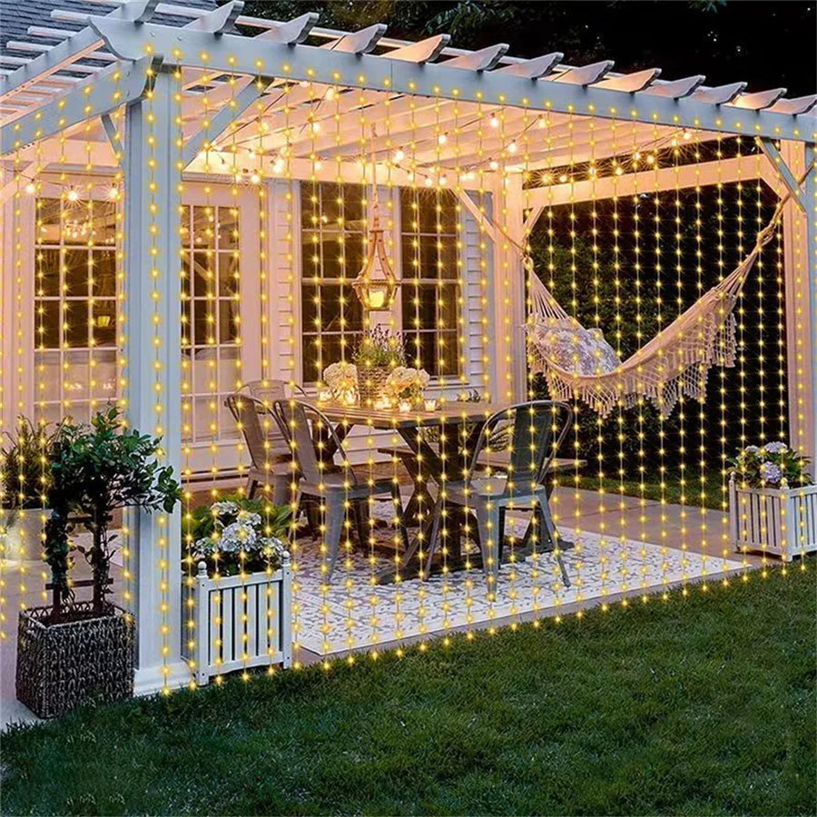 Guirlande rideau LED blanc chaud sur une pergola de jardin, le soir