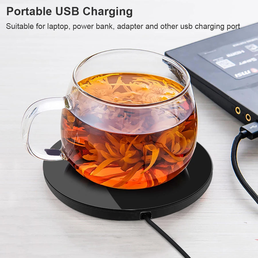 Tasse de thé en verre sur le chauffe-tasse branché en USB
